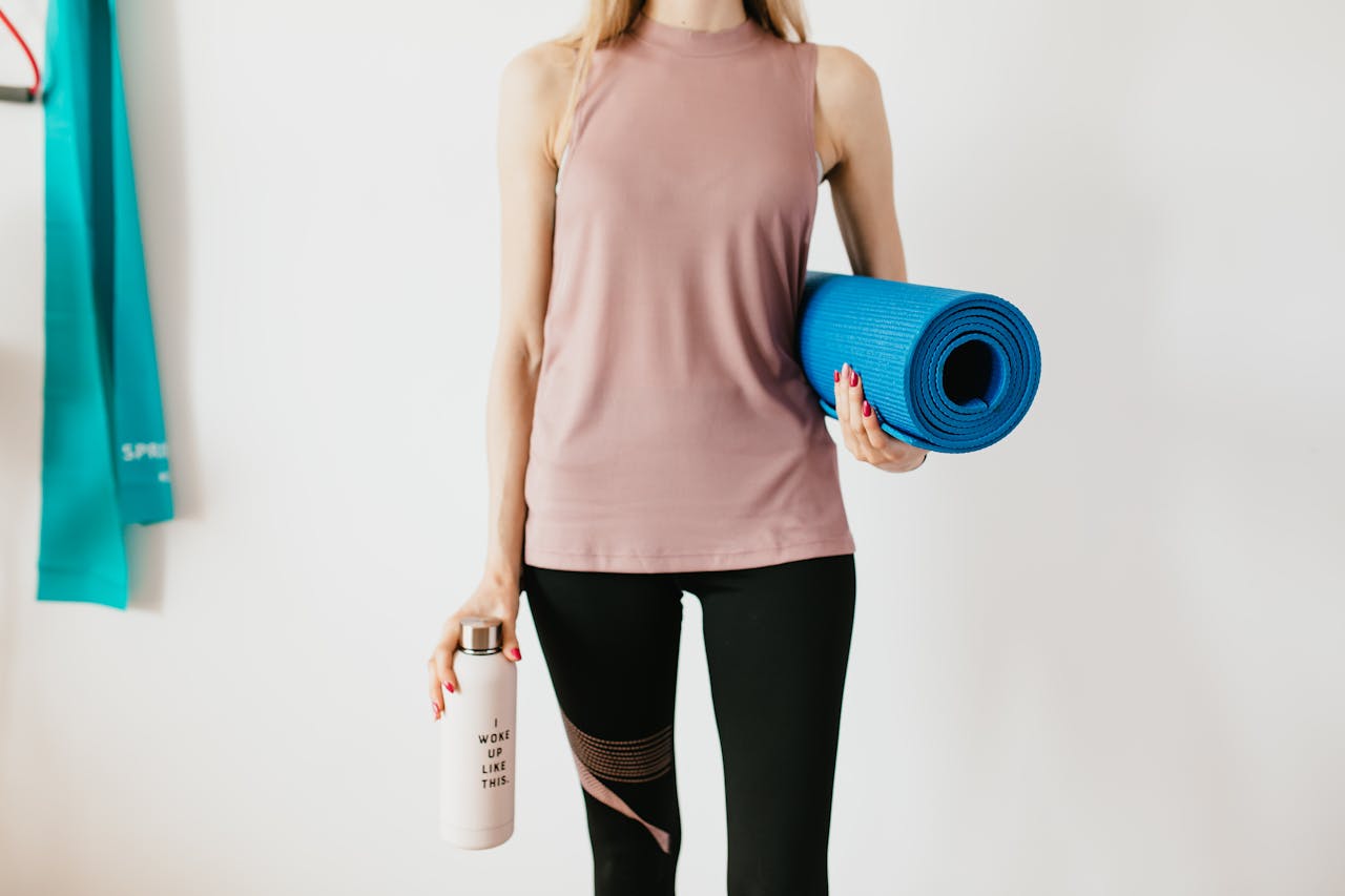 The Art of Drawing Readers In: Your attractive post title goes here Faceless slim female athlete in sportswear standing with blue fitness mat and water bottle while preparing for indoors workout